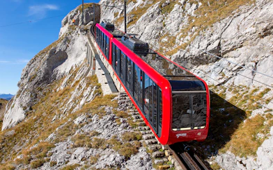 Pilatus Mountain train ascending steep rocky slope in Switzerland.