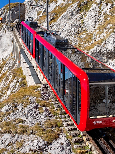 Pilatus Mountain train ascending steep rocky slope in Switzerland.