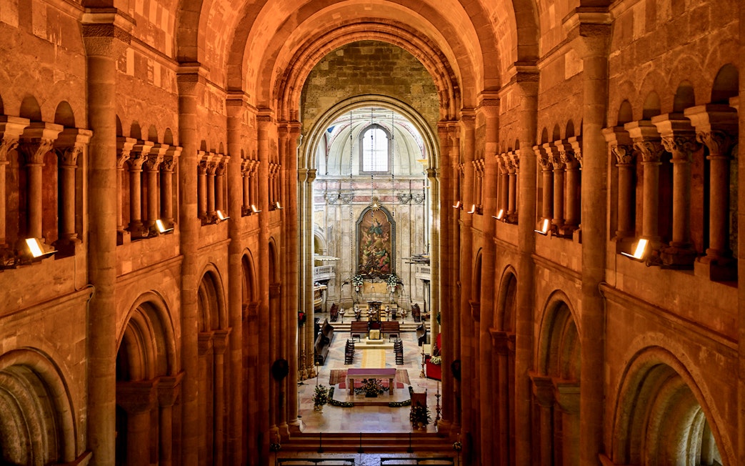 Interior view of Cathedral of Saint Mary Major, Se de Lisboa, Lisbon, Portugal, showcasing arches and altar.