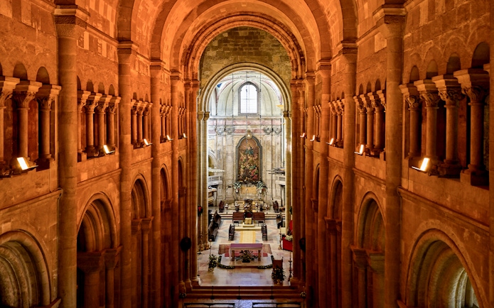 Interior view of Cathedral of Saint Mary Major, Se de Lisboa, Lisbon, Portugal, showcasing arches and altar.