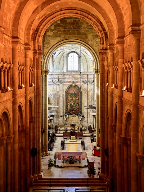 Interior view of Cathedral of Saint Mary Major, Se de Lisboa, Lisbon, Portugal, showcasing arches and altar.