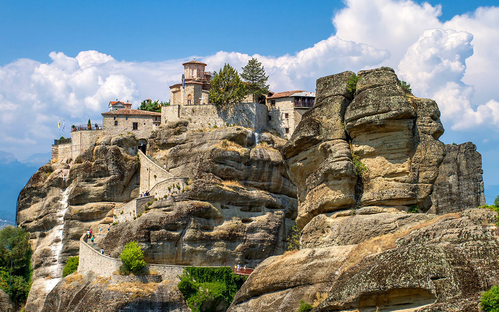 Meteora monastery perched on rock formations under a blue sky in Greece.