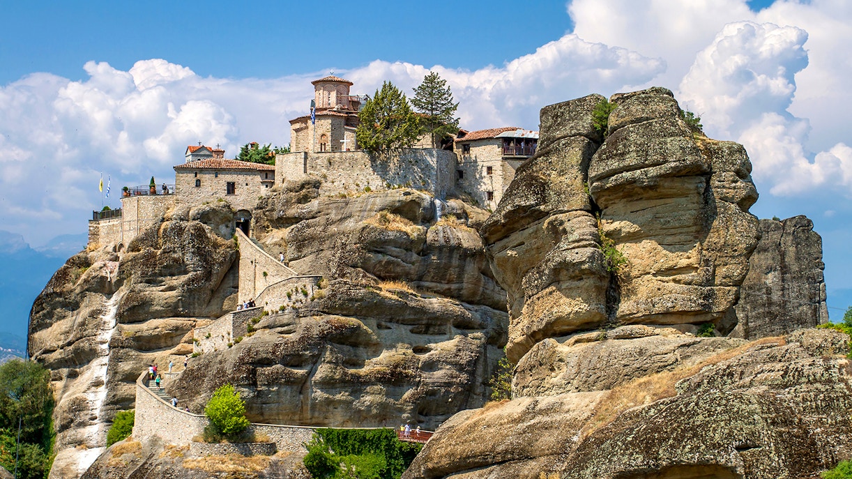 Meteora monastery perched on rock formations under a blue sky in Greece.