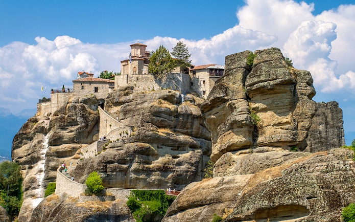 Meteora monastery perched on rock formations under a blue sky in Greece.