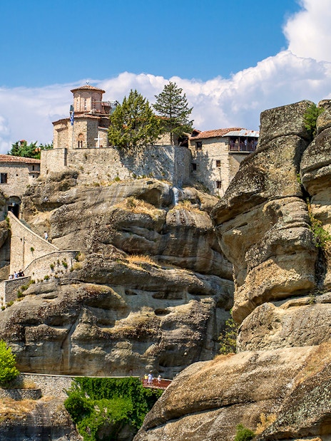 Meteora monastery perched on rock formations under a blue sky in Greece.