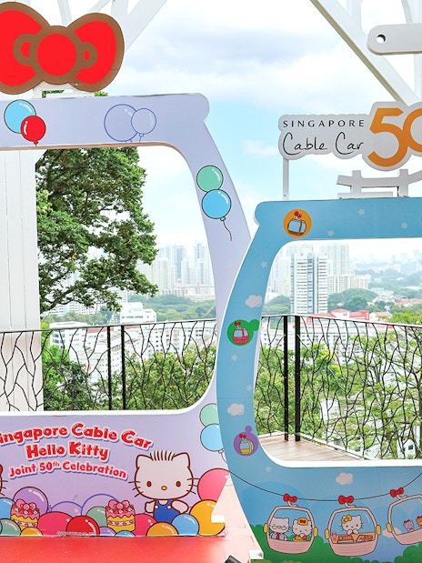 Singapore Cable Car Hello Kitty 50th celebration frame with city skyline in background.