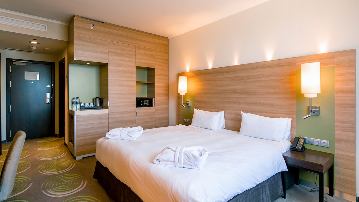 Luxury hotel bedroom interior after housekeeping cleaning, featuring neatly arranged bed and elegant decor.