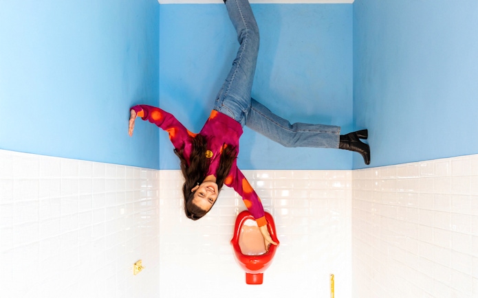 Person posing in an upside-down room at Upside Down Amsterdam.