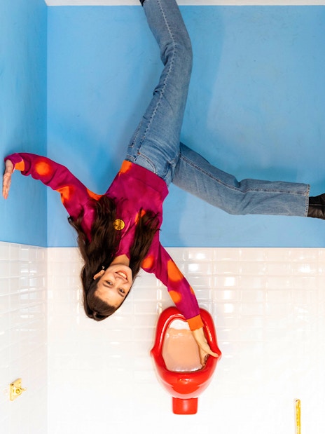 Person posing in an upside-down room at Upside Down Amsterdam.