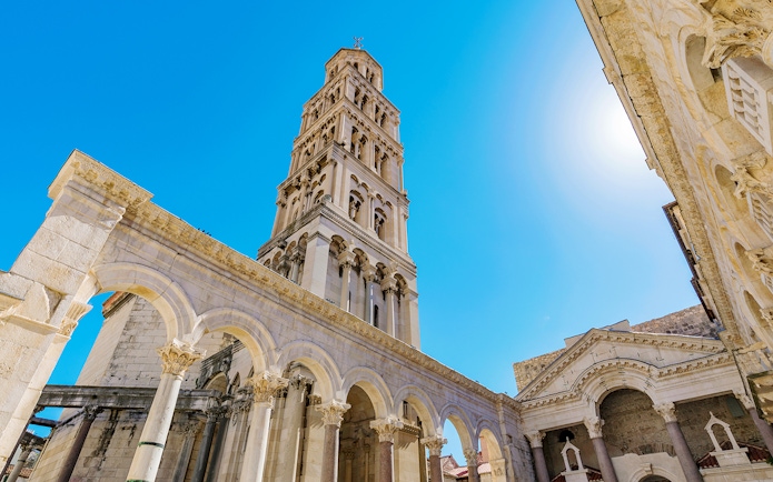 Diocletian's Palace bell tower and arches in Split, Croatia, under a clear blue sky.