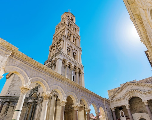 Diocletian's Palace bell tower and arches in Split, Croatia, under a clear blue sky.