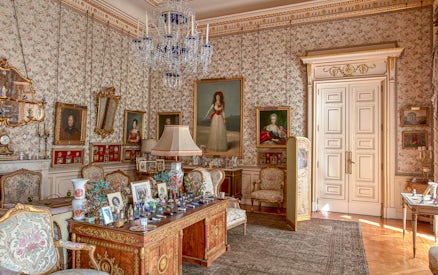 Photos and paintings in an ornate room at Liria Palace, featuring classic furniture and decor.