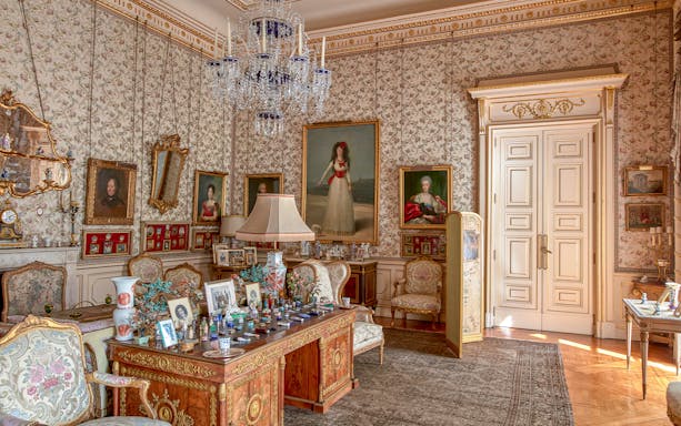 Photos and paintings in an ornate room at Liria Palace, featuring classic furniture and decor.