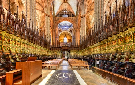 Interior of the Cathedral of Barcelona, featuring ornate choir stalls and vaulted ceilings.