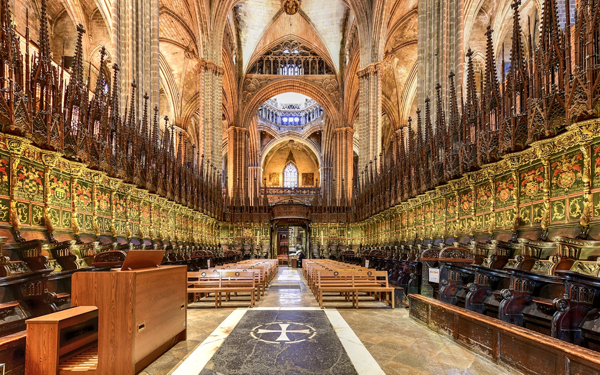 Interior of the Cathedral of Barcelona, featuring ornate choir stalls and vaulted ceilings.