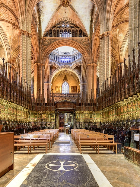 Interior of the Cathedral of Barcelona, featuring ornate choir stalls and vaulted ceilings.