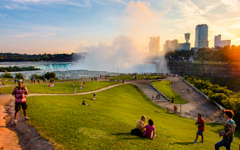 Walking tour near Niagara Falls with view of mist and city skyline.