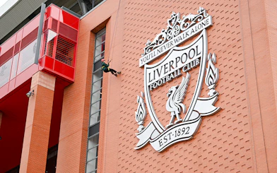 Abseiling down Anfield Stadium near Liverpool FC crest.