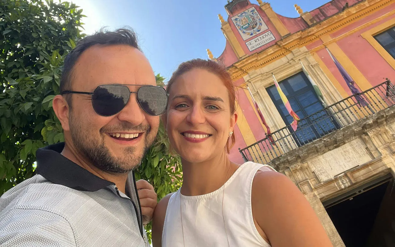 Couple smiling in front of a historic building in Seville Old Town.