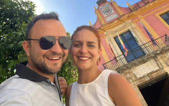 Couple smiling in front of a historic building in Seville Old Town.