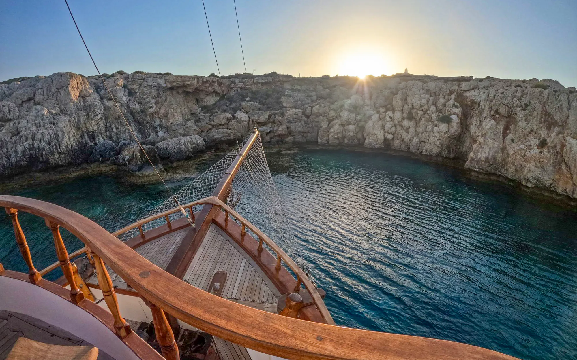 Sunset view from a boat at Blue Lagoon, Ayia Napa, with rocky cliffs and calm waters.