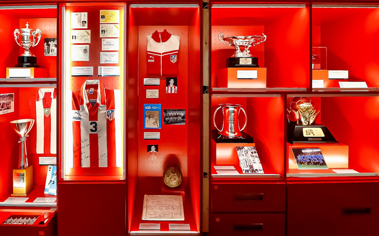 Atletico de Madrid museum display with trophies, jerseys, and memorabilia.