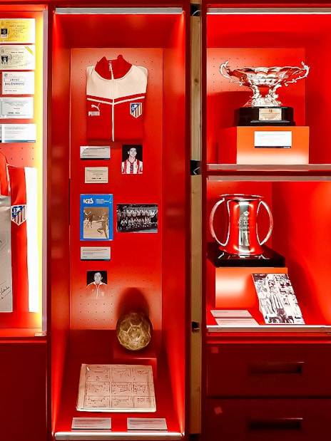 Atletico de Madrid museum display with trophies, jerseys, and memorabilia.