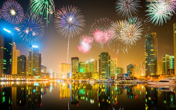 Fireworks over Dubai Marina skyline during New Year's Eve boat party near Ain Dubai and JBR.