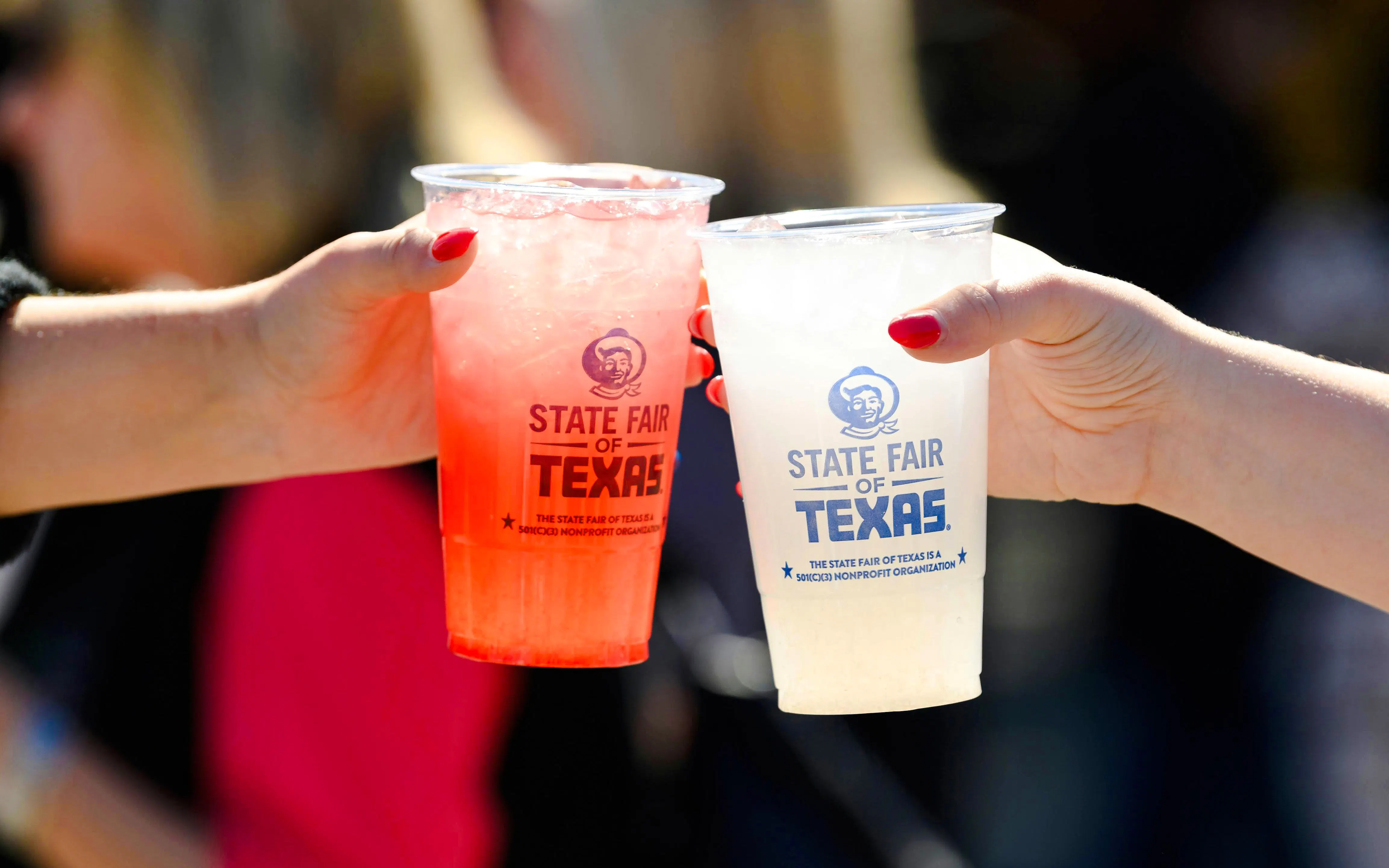 Two hands holding drinks at the State Fair of Texas.
