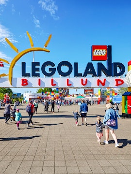 Entrance to LEGOLAND Billund with families walking towards the colorful park entrance.