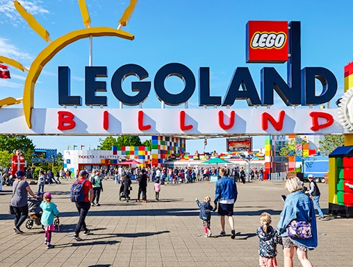 Entrance to LEGOLAND Billund with families walking towards the colorful park entrance.