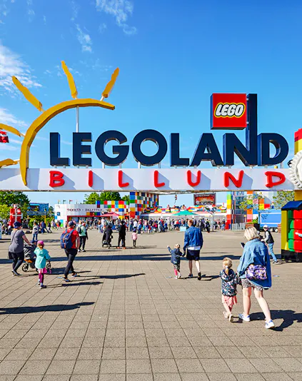 Entrance to LEGOLAND Billund with families walking towards the colorful park entrance.