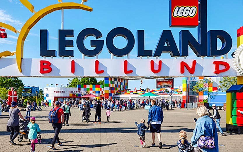 Entrance to LEGOLAND Billund with families walking towards the colorful park entrance.