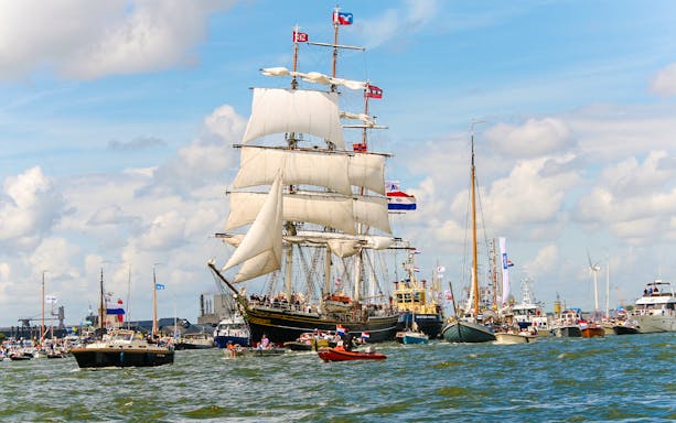 Tall ships sailing in a parade during SAIL Amsterdam event, showcasing maritime heritage in the Netherlands.