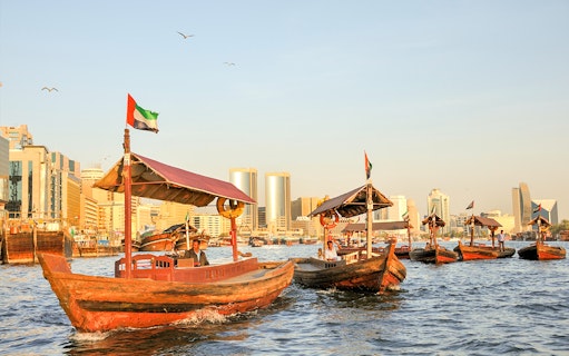 Traditional abras on Dubai Creek with city skyline in the background.