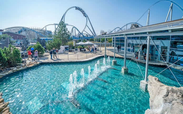 Atlantica SuperSplash ride with fountains and roller coaster in the background.