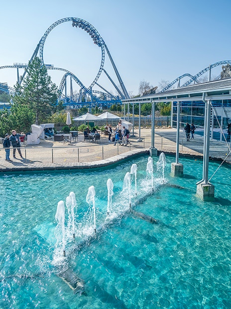 Atlantica SuperSplash ride with fountains and roller coaster in the background.