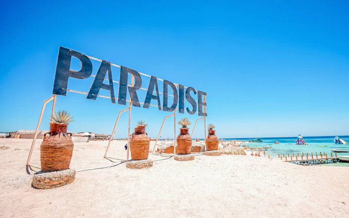 Paradise sign on sandy beach with clear blue water, Orange Bay, Giftun Island, Hurghada.