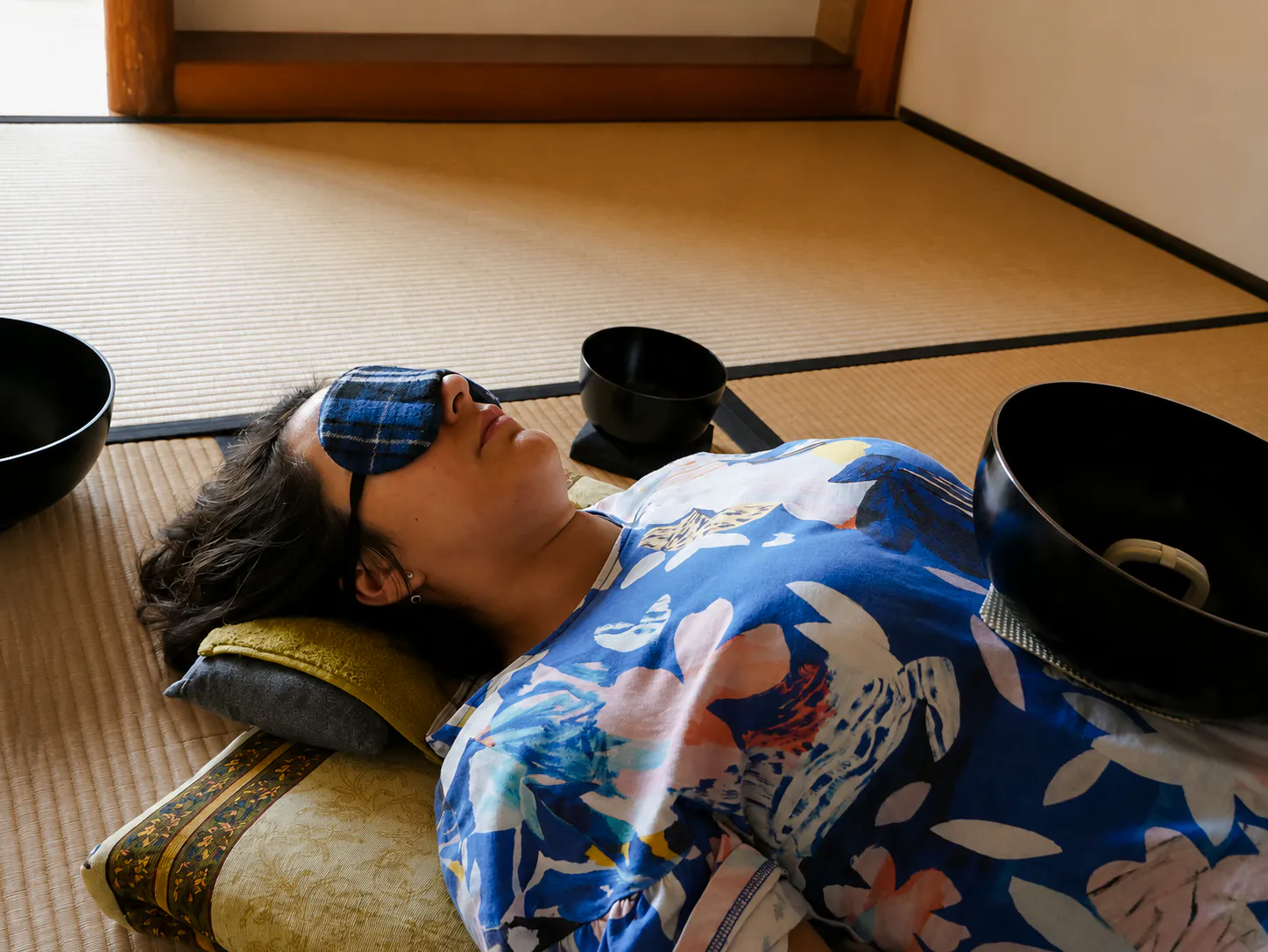 Person experiencing a Japanese sound bath with bowls on a tatami mat in Kyoto.