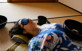Person experiencing a Japanese sound bath with bowls on a tatami mat in Kyoto.