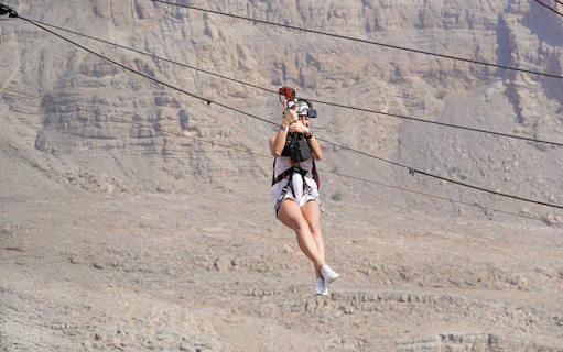 Person ziplining over rocky landscape in Jais, UAE.