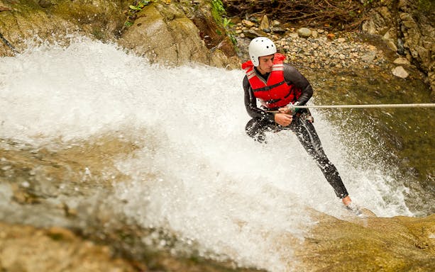 Canyoning in Varziela River, Castro Laboreiro, person rappelling down waterfall.