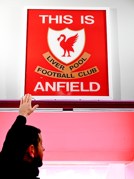 Hand touching "This is Anfield" sign at Liverpool FC's Anfield Stadium.