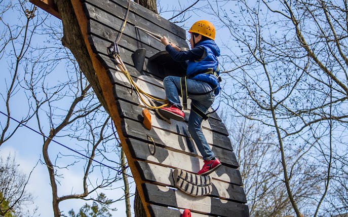 Climber on an adventure course wall at Paradis Land.
