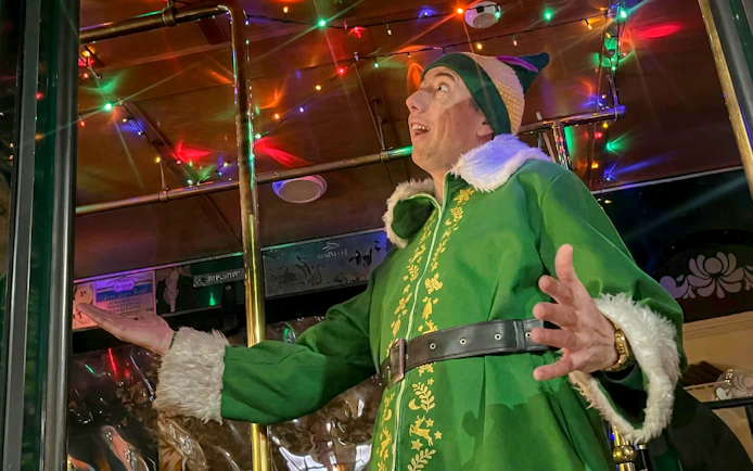 Person in festive costume on decorated trolley during San Diego's Holiday Sights Tour.