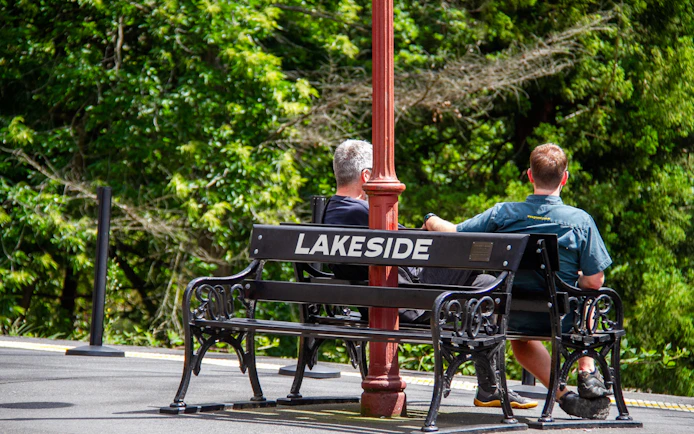 Two people sitting on a bench at Lakeside station platform during Puffing Billy tour.