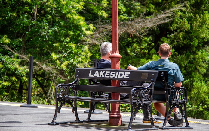 Two people sitting on a bench at Lakeside station platform during Puffing Billy tour.