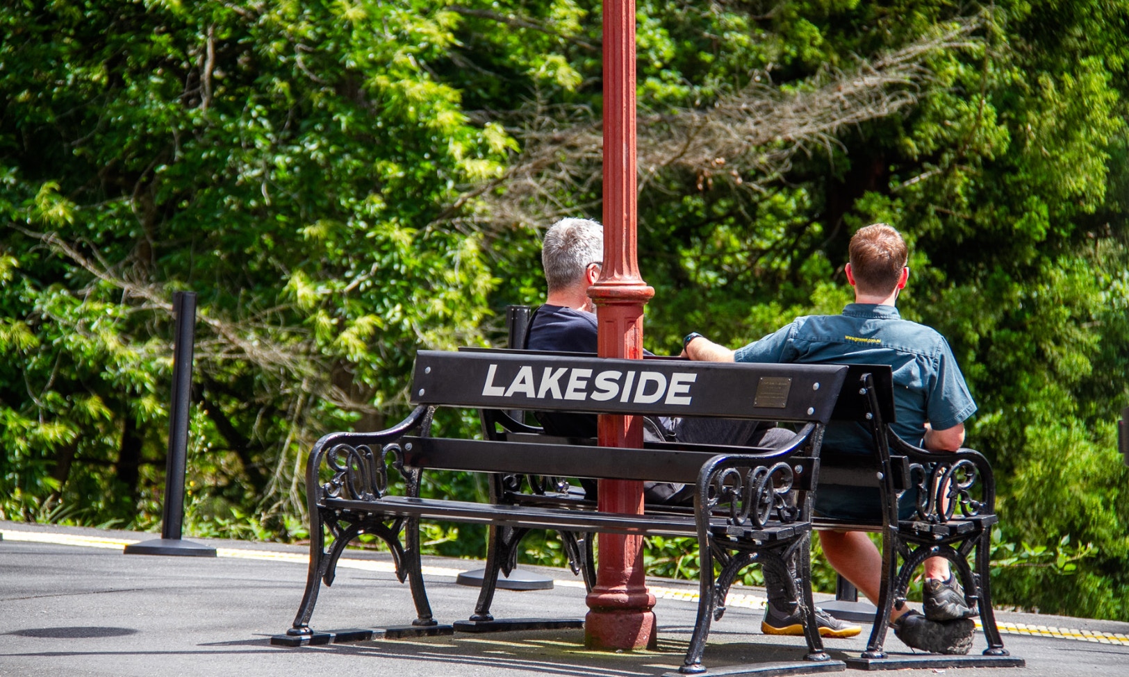 Two people sitting on a bench at Lakeside station platform during Puffing Billy tour.