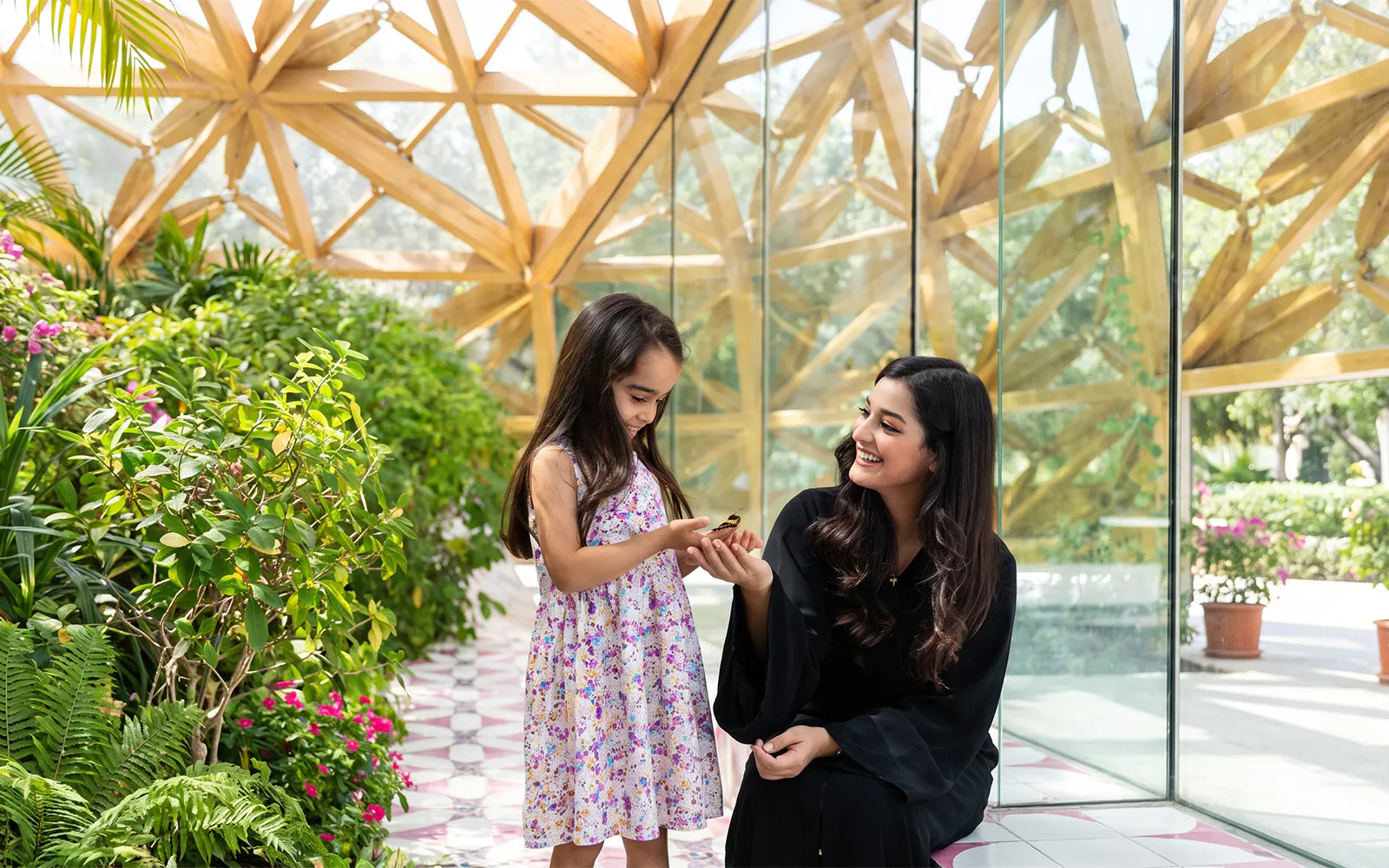 Child and woman enjoying butterfly at Al Noor Island Butterfly House.