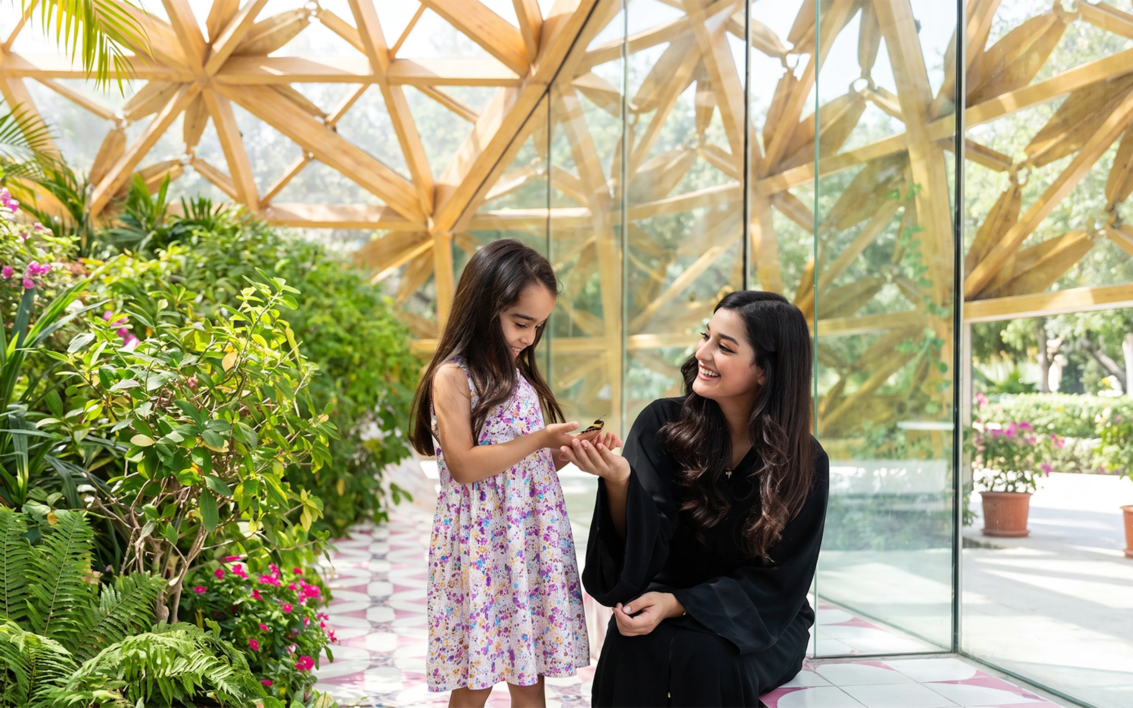Child and woman enjoying butterfly at Al Noor Island Butterfly House.